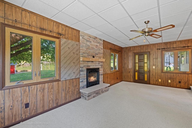 15 Wilson Ave, Fort Atkinson, WI 53538 - unfurnished living room featuring wood walls, carpet floors, a large fireplace, ceiling fan, and baseboards
