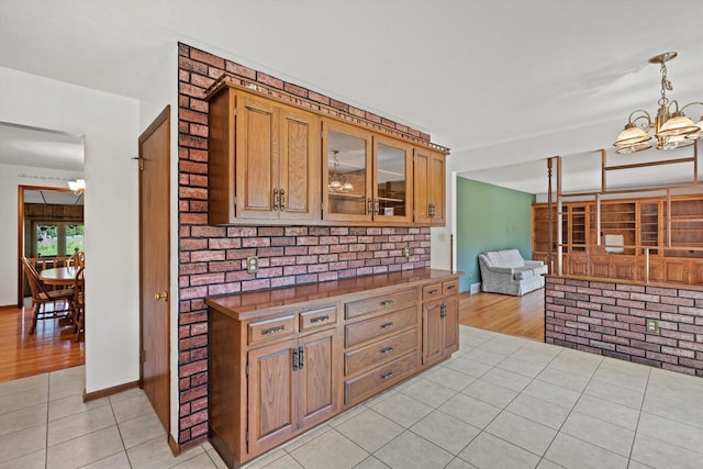 15 Wilson Ave, Fort Atkinson, WI 53538 - kitchen with a chandelier, light tile patterned floors, glass insert cabinets, and brown cabinetry