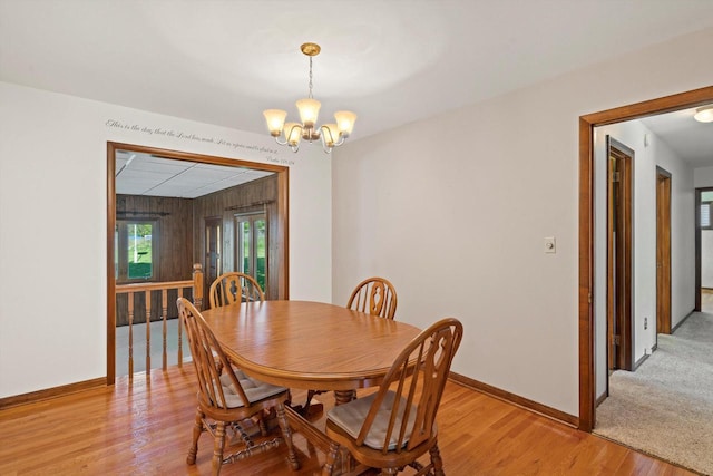 15 Wilson Ave, Fort Atkinson, WI 53538 - dining area featuring a chandelier, light wood-style flooring, baseboards, and wood walls