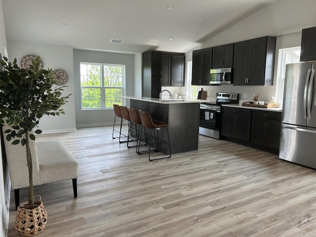 W141N9978 Seven Pines Way Unit 204, Germantown, WI 53022 - kitchen with stainless steel appliances, dark cabinets, a kitchen bar, lofted ceiling, and light countertops