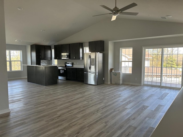W141N9978 Seven Pines Way Unit 204, Germantown, WI 53022 - kitchen featuring appliances with stainless steel finishes, open floor plan, light countertops, baseboards, and high vaulted ceiling