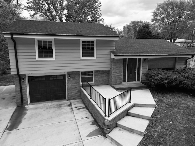 13460 Tremont St, Brookfield, WI 53005 - split level home with concrete driveway, a garage, brick siding, and a shingled roof