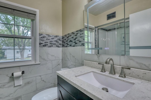 13460 Tremont St, Brookfield, WI 53005 - full bath featuring vanity, toilet, tile walls, healthy amount of natural light, and a shower stall