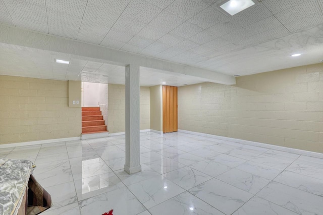 13460 Tremont St, Brookfield, WI 53005 - finished below grade area with marble look tiles, stairs, concrete block wall, and baseboards