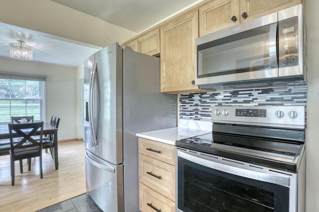 13460 Tremont St, Brookfield, WI 53005 - kitchen featuring stainless steel appliances, light brown cabinets, decorative backsplash, light countertops, and a chandelier