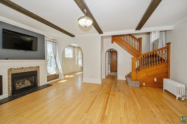 2127 Tower Ave, Superior, WI 54880 - unfurnished living room featuring radiator heating unit, arched walkways, beamed ceiling, stairs, and hardwood / wood-style floors
