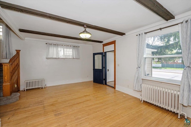 2127 Tower Ave, Superior, WI 54880 - spare room featuring radiator heating unit, beamed ceiling, plenty of natural light, and light wood finished floors