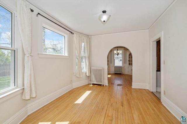 2127 Tower Ave, Superior, WI 54880 - spare room with radiator, arched walkways, light wood-type flooring, and healthy amount of natural light