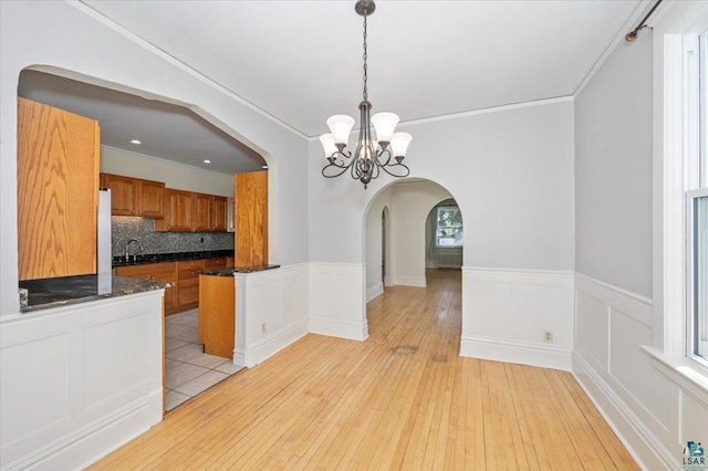 2127 Tower Ave, Superior, WI 54880 - unfurnished dining area featuring arched walkways, a chandelier, crown molding, light wood-type flooring, and a sink