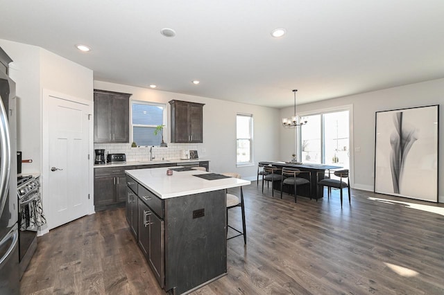 704 River Ridge Drive, Waterford, WI 53185 - kitchen featuring stainless steel range with gas cooktop, a breakfast bar, a chandelier, a sink, and light countertops