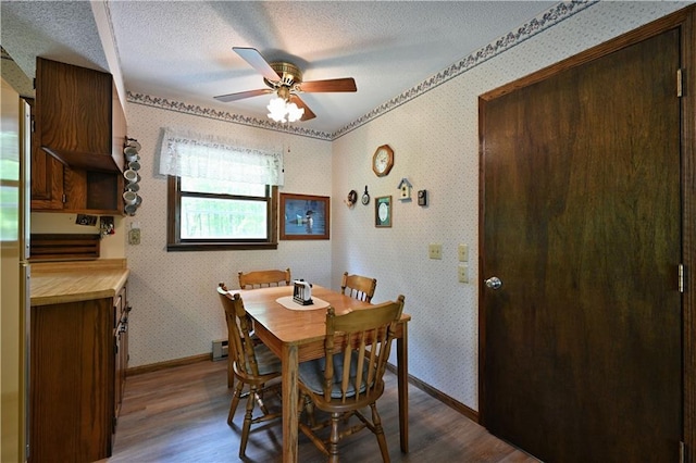 W2847 County Highway B, Sarona, WI 54870 - dining room with dark wood-style floors, ceiling fan, baseboards, wallpapered walls, and a textured ceiling
