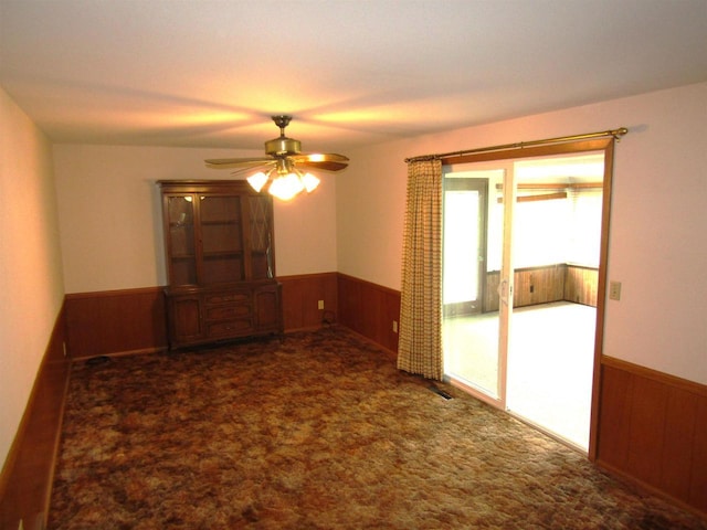 2374 S Park Ave, Beloit, WI 53511 - spare room featuring wainscoting, wooden walls, ceiling fan, and carpet