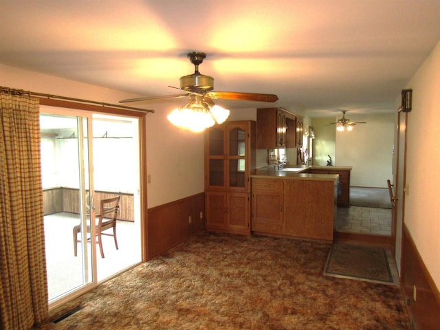2374 S Park Ave, Beloit, WI 53511 - kitchen featuring ceiling fan, a peninsula, brown cabinetry, plenty of natural light, and wainscoting