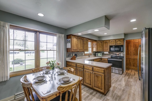 4034 Chicory Rd, Mount Pleasant, WI 53403 - kitchen featuring stainless steel appliances, a peninsula, brown cabinetry, light wood-style floors, and tasteful backsplash