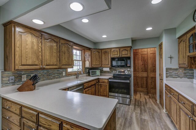 4034 Chicory Rd, Mount Pleasant, WI 53403 - kitchen with appliances with stainless steel finishes, tasteful backsplash, brown cabinets, a peninsula, and light wood-type flooring