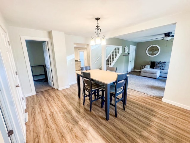 509 E Jefferson St, Stoughton, WI 53589 - dining space with baseboards, light wood finished floors, stairs, a chandelier, and ceiling fan