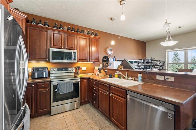 1300 School St Unit 209, Sun Prairie, WI 53590 - kitchen featuring stainless steel appliances, a sink, a peninsula, light tile patterned flooring, and hanging light fixtures