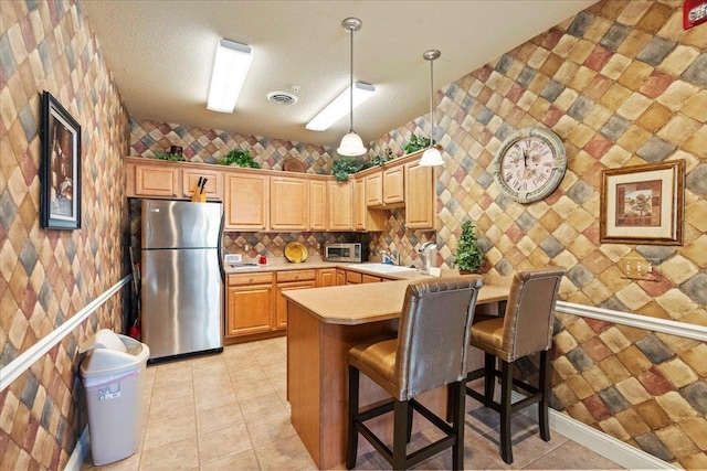 1300 School St Unit 209, Sun Prairie, WI 53590 - kitchen featuring appliances with stainless steel finishes, light countertops, a kitchen bar, wallpapered walls, and decorative light fixtures