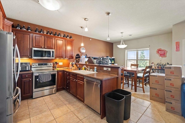 1300 School St Unit 209, Sun Prairie, WI 53590 - kitchen with appliances with stainless steel finishes, a sink, a peninsula, hanging light fixtures, and light tile patterned floors