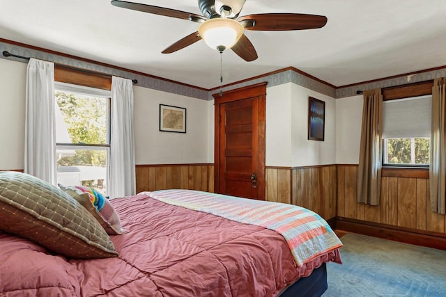 202 Lake St, Mount Horeb, WI 53572 - carpeted bedroom featuring multiple windows, wood walls, wainscoting, and ceiling fan