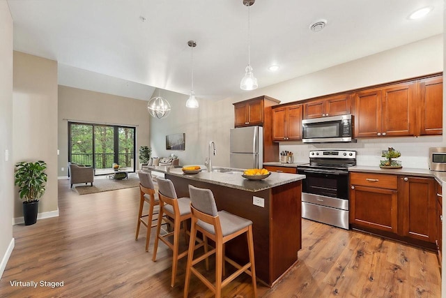1512 Lake St, Baraboo, WI 53913 - kitchen featuring stainless steel appliances, backsplash, a kitchen breakfast bar, brown cabinetry, and wood finished floors