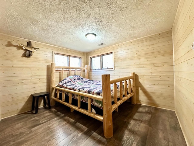 N11893 Pratt Rd, Elcho, WI 54428 - bedroom featuring wood walls, dark wood-style flooring, and a textured ceiling