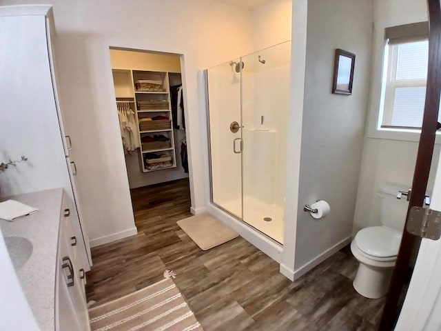 1890 Red Fox Ln, Kaukauna, WI 54130 - bathroom with wood finished floors, a stall shower, a spacious closet, toilet, and baseboards