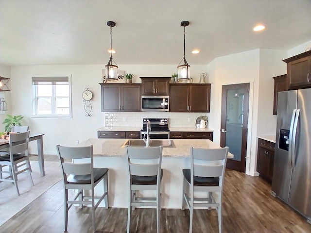 1890 Red Fox Ln, Kaukauna, WI 54130 - kitchen featuring appliances with stainless steel finishes, decorative backsplash, dark brown cabinets, dark wood-style floors, and light stone counters