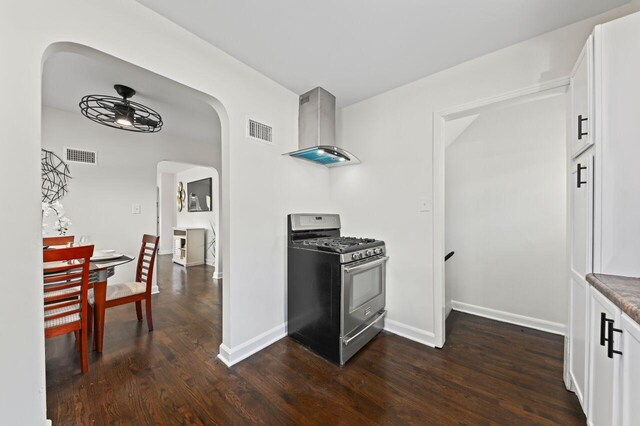 5002 N 24th Pl, Milwaukee, WI 53209 - kitchen with stainless steel range with gas cooktop, wall chimney exhaust hood, arched walkways, and dark wood finished floors