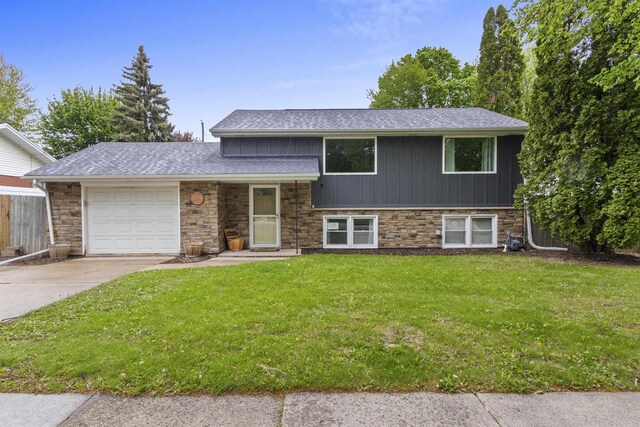 1254 Thorndale St, Green Bay, WI 54304 - tri-level home featuring an attached garage, a shingled roof, a front lawn, concrete driveway, and stone siding