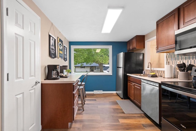 1254 Thorndale St, Green Bay, WI 54304 - kitchen with appliances with stainless steel finishes, light countertops, wood finished floors, backsplash, and baseboards