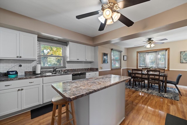 4683 N 80th St, Milwaukee, WI 53218 - kitchen with a sink, a wainscoted wall, wood finished floors, white cabinetry, and decorative backsplash