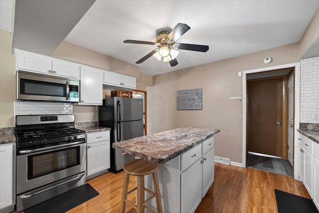 4683 N 80th St, Milwaukee, WI 53218 - kitchen featuring appliances with stainless steel finishes, ceiling fan, tasteful backsplash, white cabinets, and light wood-style floors