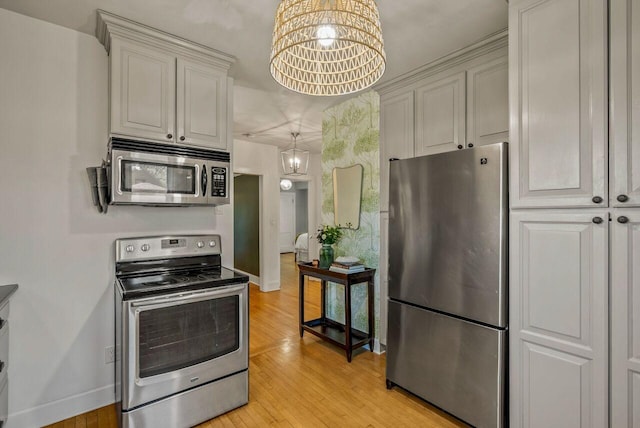 5642 N Argyle Ave, Glendale, WI 53209 - kitchen with stainless steel appliances, a chandelier, baseboards, and light wood finished floors