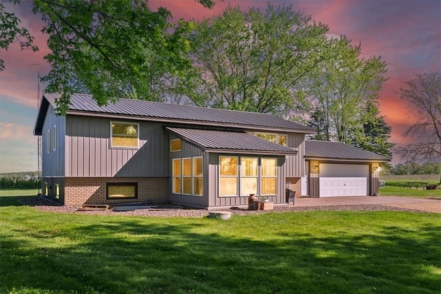 E7065 E County Road B, Colfax, WI 54730 - back of property at dusk featuring an attached garage, dirt driveway, a yard, and metal roof