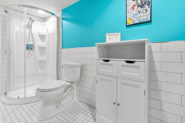 208 Edgewood Dr, Neenah, WI 54956 - bathroom with tile walls, toilet, a stall shower, wainscoting, and tile patterned floors