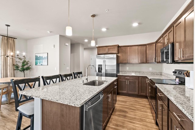 4857 Suelo Rd, Fitchburg, WI 53711 - kitchen featuring stainless steel appliances, a sink, a kitchen breakfast bar, light wood finished floors, and recessed lighting