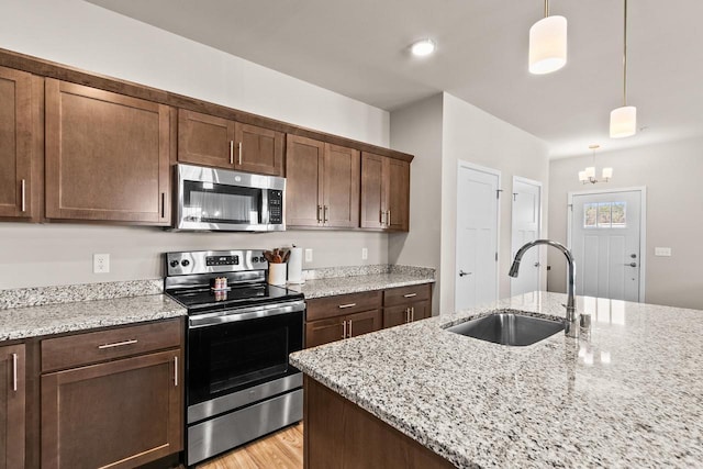 4857 Suelo Rd, Fitchburg, WI 53711 - kitchen with appliances with stainless steel finishes, a sink, hanging light fixtures, a chandelier, and light stone countertops