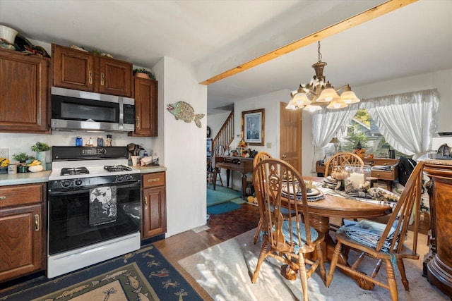 N53W34956 Rd B, Okauchee, WI 53069 - kitchen featuring stainless steel microwave, gas stove, a chandelier, light countertops, and dark wood-style flooring