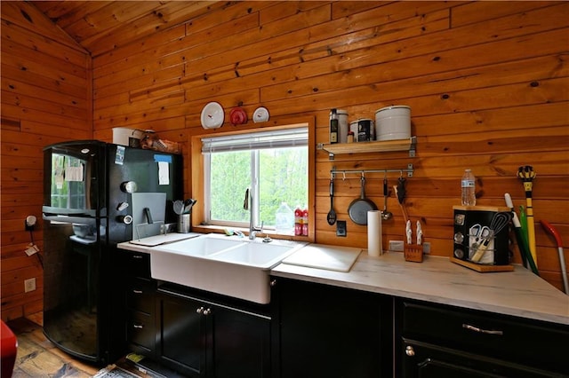 82912 Augustine Rd, Glidden, WI 54527 - kitchen featuring dark cabinets, freestanding refrigerator, a sink, wooden walls, and vaulted ceiling