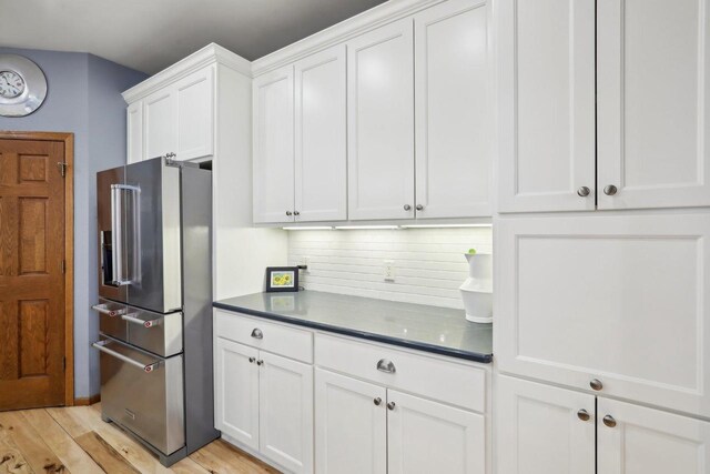 10 Prairie Hill Ct, Madison, WI 53719 - kitchen featuring high quality fridge, dark countertops, white cabinetry, decorative backsplash, and light wood-type flooring