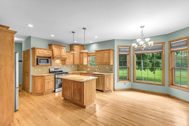 N74W28801 Zimmers Xing, Hartland, WI 53029 - kitchen featuring appliances with stainless steel finishes, light wood-style floors, a center island, a chandelier, and tasteful backsplash