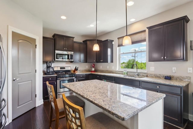 417 Champlain Dr, Johnson Creek, WI 53038 - kitchen with stainless steel appliances, a sink, a breakfast bar, dark brown cabinetry, and dark wood finished floors