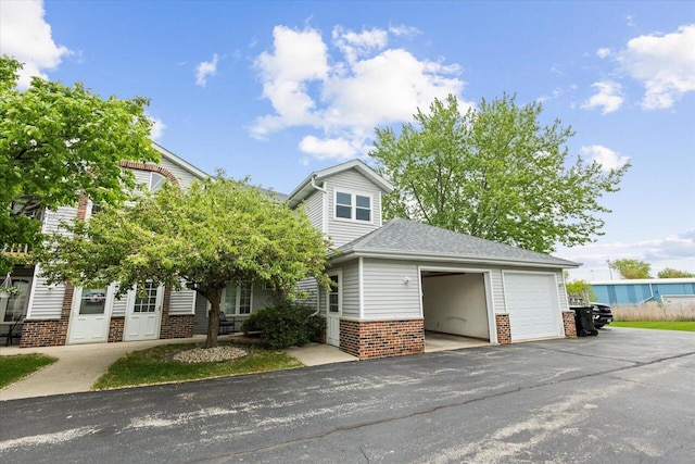 514 Root Ave Unit D, Hartford, WI 53027 - view of property hidden behind natural elements featuring brick siding and a garage