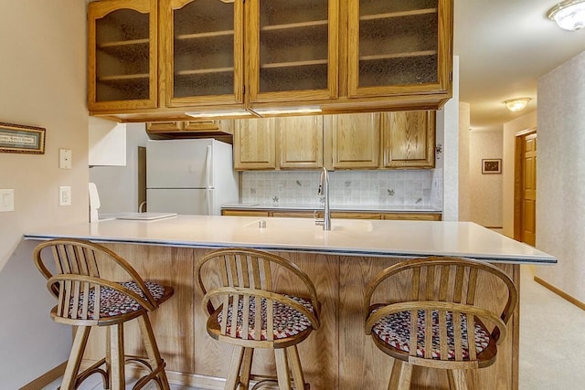 211 Oconomowoc Pkwy, Oconomowoc, WI 53066 - kitchen with freestanding refrigerator, backsplash, a kitchen bar, and glass insert cabinets