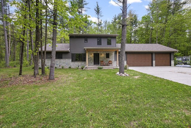 W2434 Timber Trl, Keshena, WI 54135 - view of front of property with an attached garage, a front yard, concrete driveway, stone siding, and covered porch