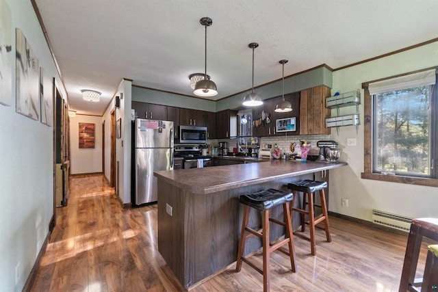 3910 E Koenig Rd, Superior, WI 54880 - kitchen featuring stainless steel appliances, dark countertops, a peninsula, backsplash, and wood finished floors