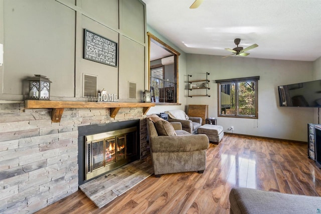 3910 E Koenig Rd, Superior, WI 54880 - living area featuring a ceiling fan, vaulted ceiling, wood finished floors, a stone fireplace, and baseboards
