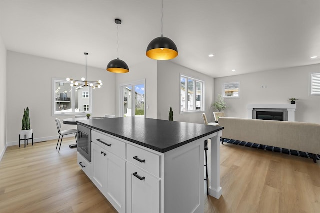 727 Schubert St, Verona, WI 53593 - kitchen featuring dark countertops, light wood-style flooring, a fireplace, white cabinetry, and stainless steel microwave