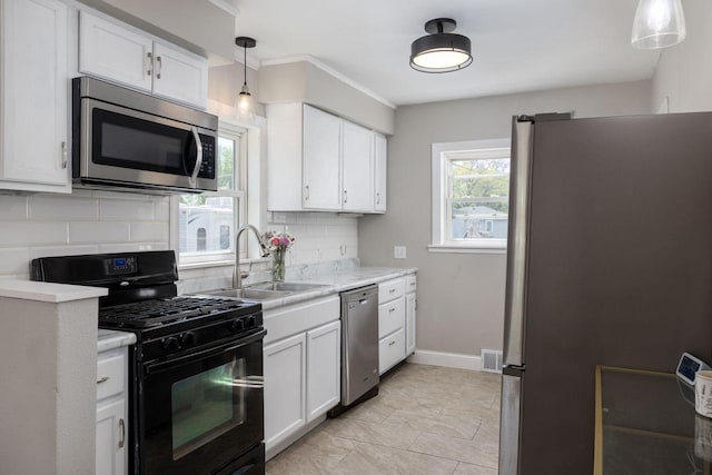 2801 Harvey St, La Crosse, WI 54603 - kitchen featuring appliances with stainless steel finishes, a sink, light countertops, tasteful backsplash, and white cabinetry